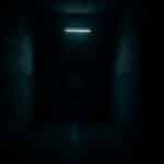 Couloir sombre éclairé par une lumière vacillante, symbole du suspense et du hors-champ dans les films d’horreur.