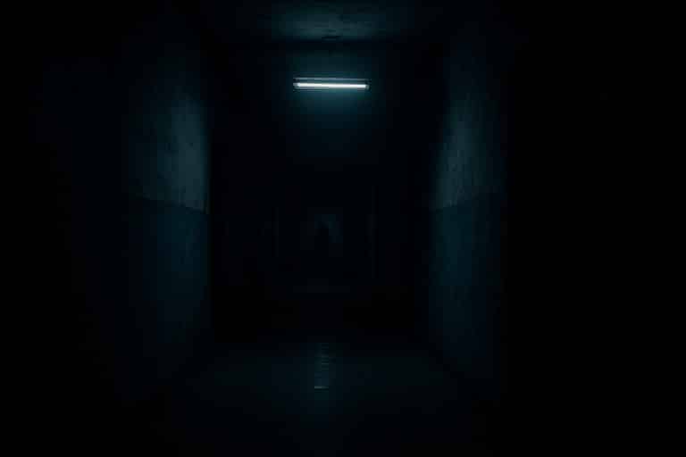 Couloir sombre éclairé par une lumière vacillante, symbole du suspense et du hors-champ dans les films d’horreur.